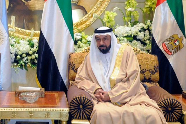Sheikh Khalifa bin Zayed bin Sultan, second president of the UAE, sits in front of the UAE flag.