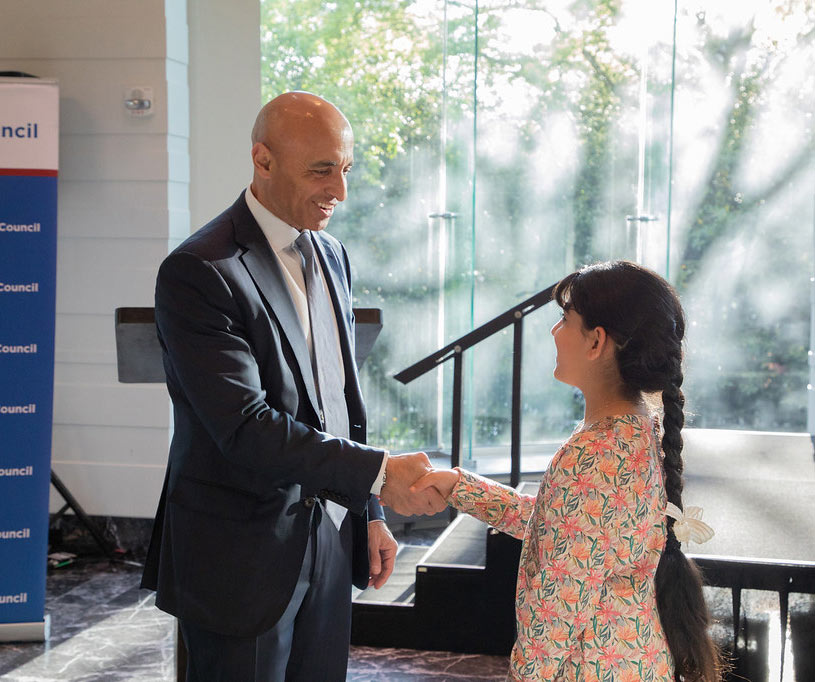 Ambassador Yousef Al Otaiba congratulates a young person with a handshake.