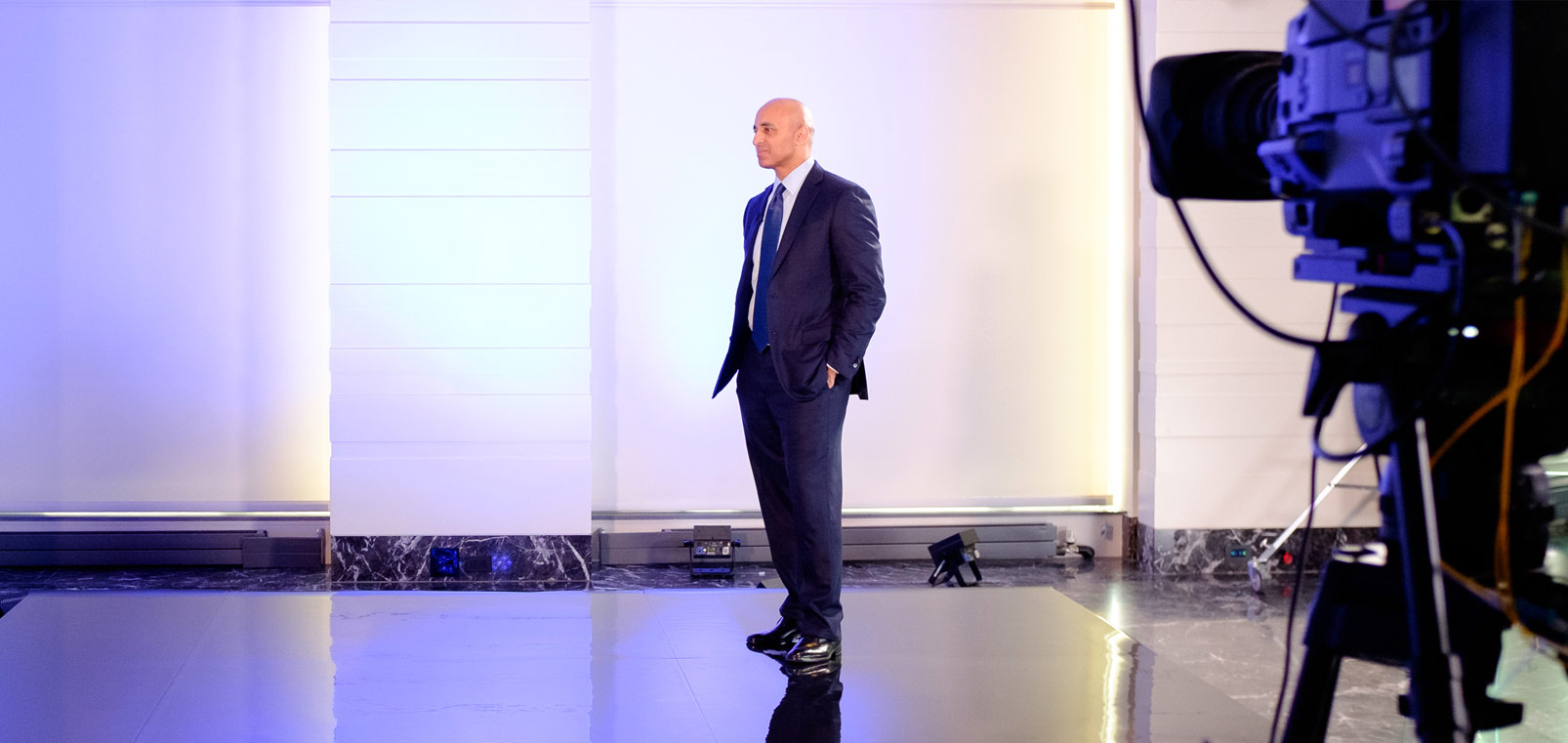 Ambassador Yousef Al Otaiba stands on stage at a virtual event celebrating the UAE's National Day.