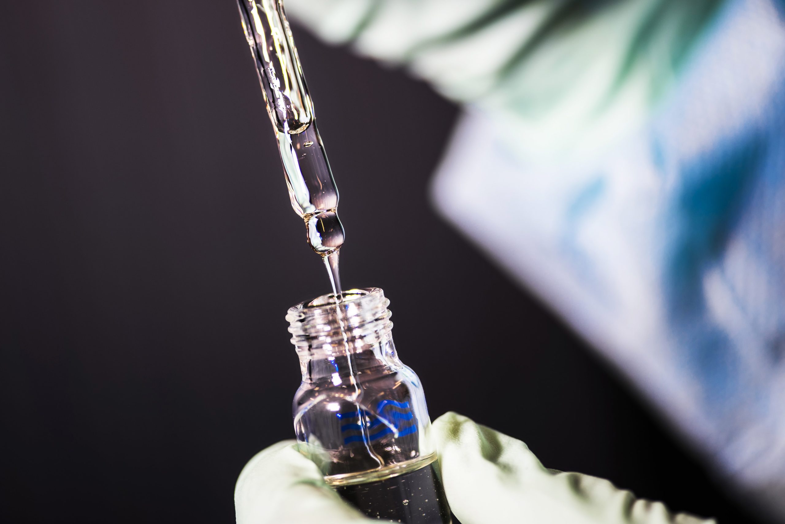 close view of a laboratory technician in the process of pipetting a sample of vitamin E acetate