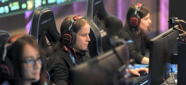 Three young women gaming on computers at the Monumental Sports & Entertainment (MSE) event.