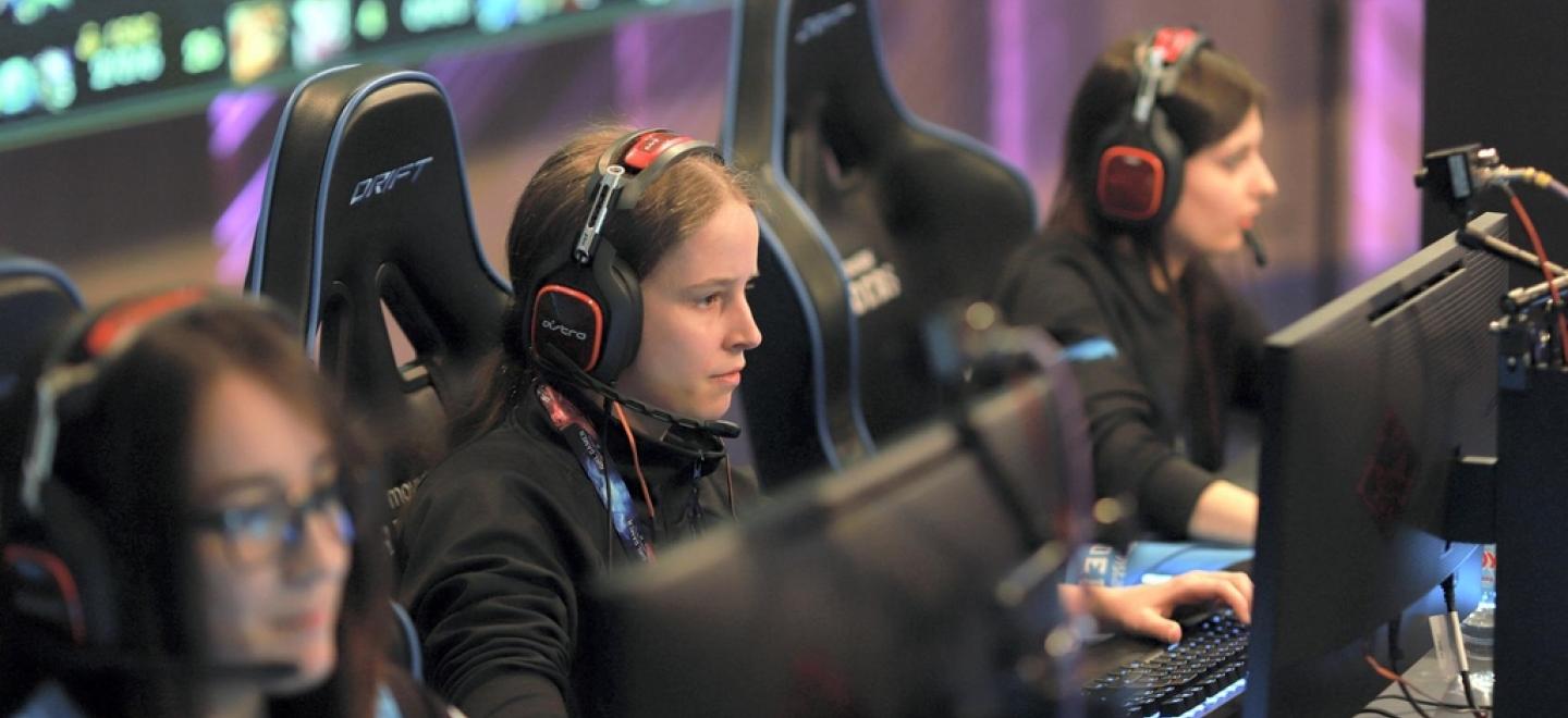 Three young women gaming on computers at the Monumental Sports & Entertainment (MSE) event.